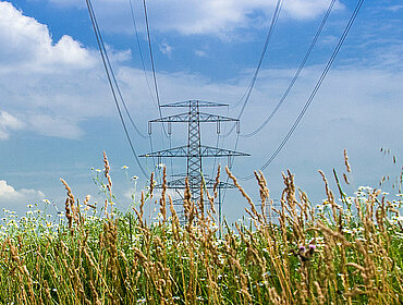 Strommast und Windräder in der Landschaft