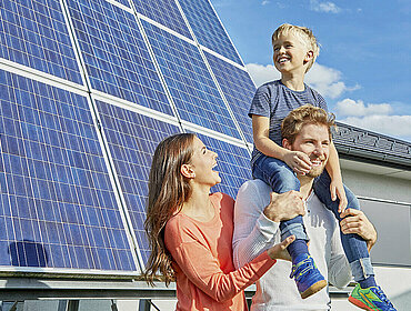 Familie steht vor einer PV-Anlage