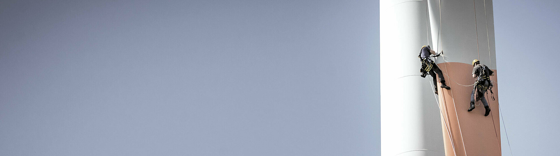 Inspektionsingenieure seilen sich an einem Rotorblatt einer Windturbine ab