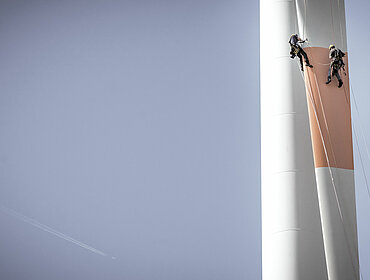 Inspektionsingenieure seilen sich an einem Rotorblatt einer Windturbine ab