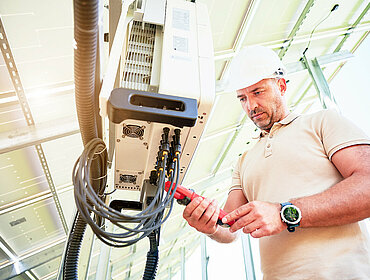 Arbeiter überprüft die Arbeit des Solarwechselrichters.