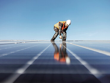 Ein Handwerker verwendet einen Schraubendreher, um Solarpaneele auf dem Dach zu installieren.