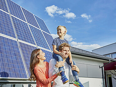 Familie steht vor einer PV-Anlage