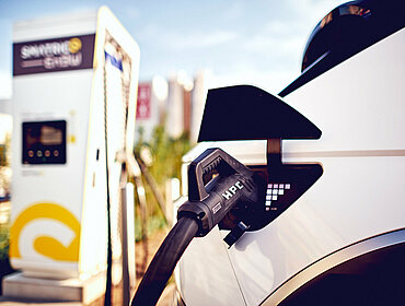 Ein Elektroauto steht neben einer Ladestation und wird mit Strom geladen.