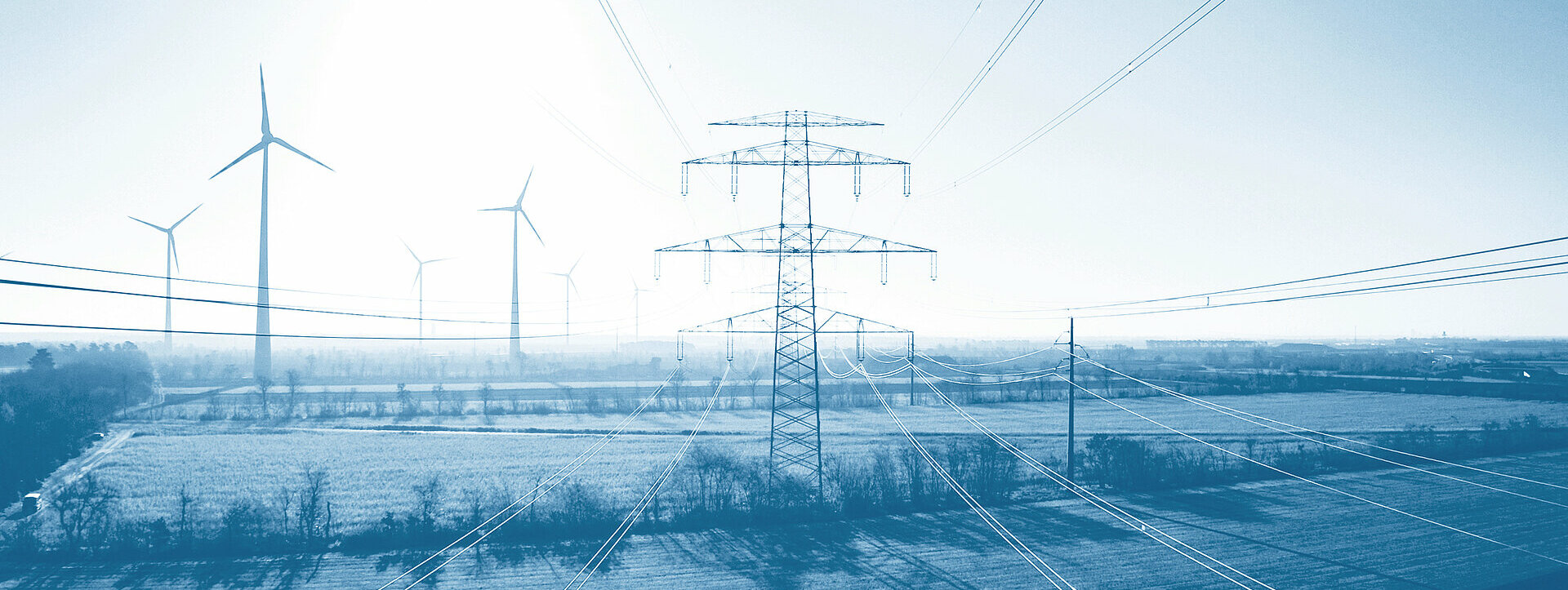 Übertragungsnetze Windräder und Übertragungsnetze in einer Landschaft an einem sonnigen Tag.