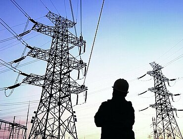 Am Abend: Silhouette von Stromarbeitern und Strommasten, Energiearbeiter bei der Arbeit